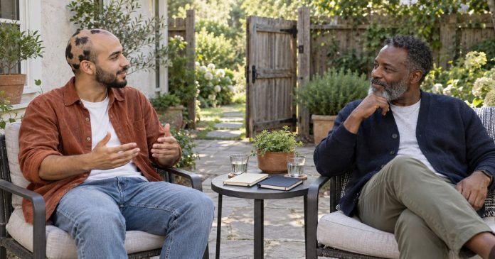 Two men speaking with personal space beside an open garden gate on a backyard patio